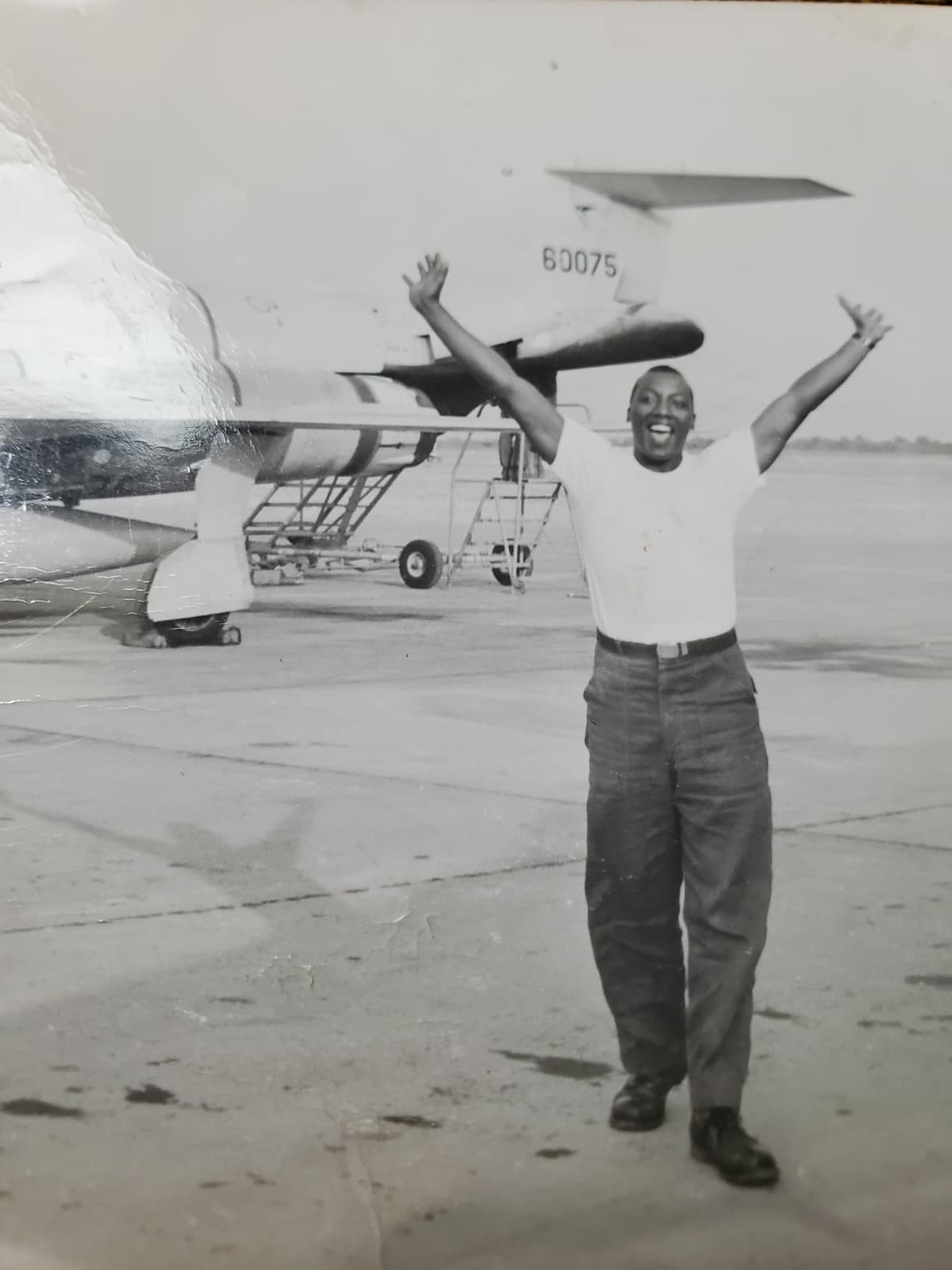 Ronald English on the flight line with arms raised in celebration beside a military jet