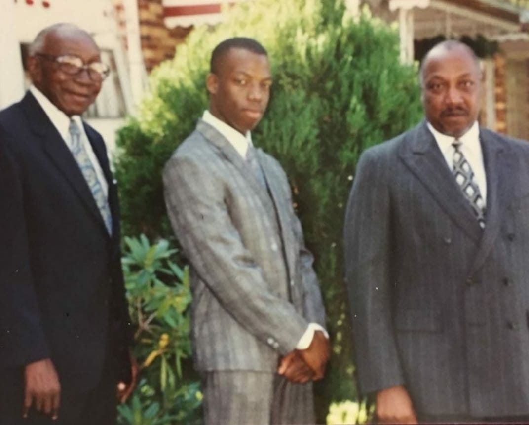 Rev. Ronald W. English standing in his suit with family outside on a Sunday