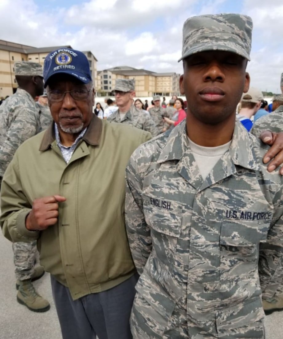 Ronald English in an Air Force Retired cap standing with his son in uniform at a base ceremony